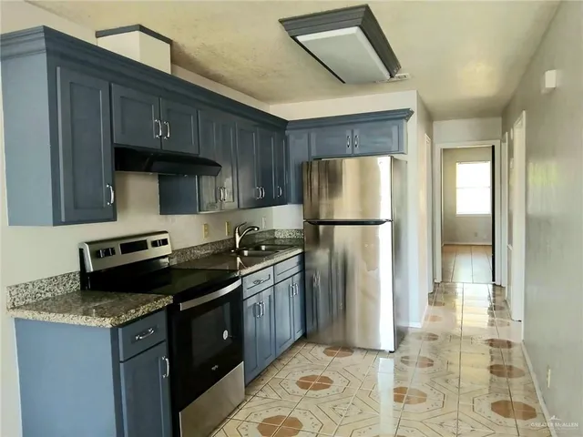 a kitchen with stainless steel appliances granite countertop a stove a refrigerator and a sink
