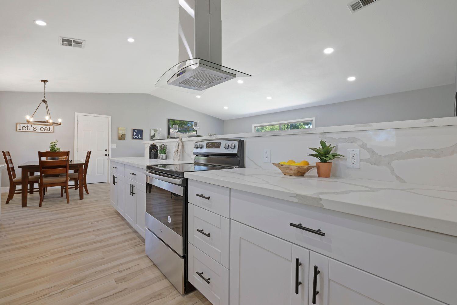 a kitchen with stainless steel appliances a sink a stove and chairs