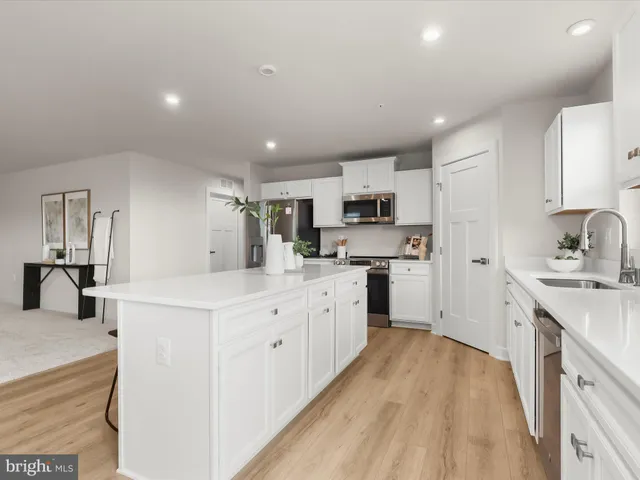 a living room with stainless steel appliances kitchen island granite countertop furniture and a wooden floor