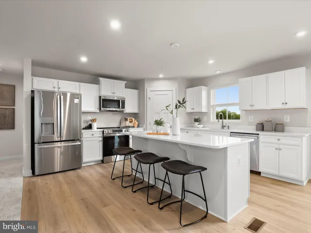 a dining room with stainless steel appliances kitchen island granite countertop a dining table chairs and a refrigerator