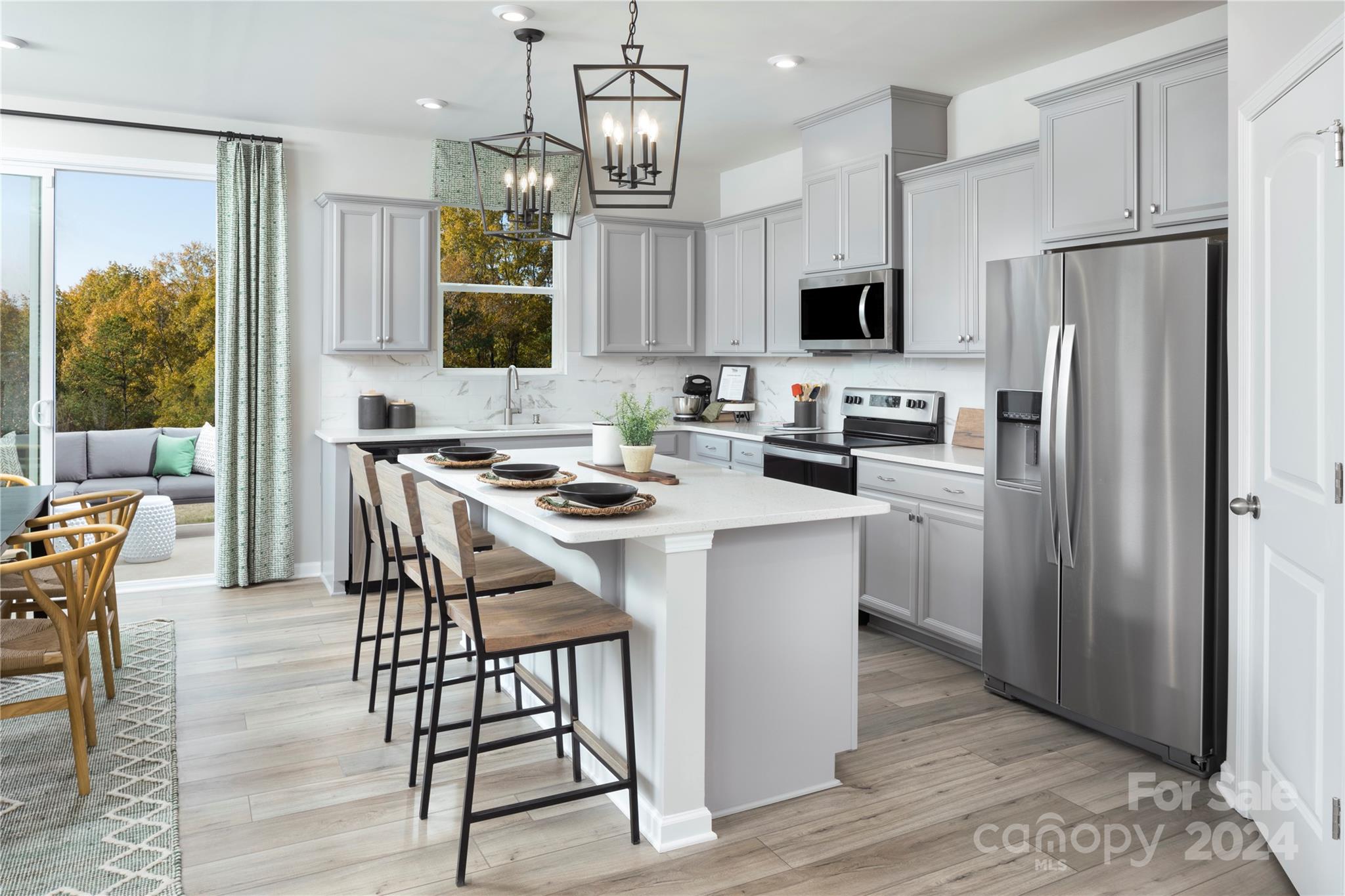 a kitchen with stainless steel appliances a table chairs refrigerator and microwave
