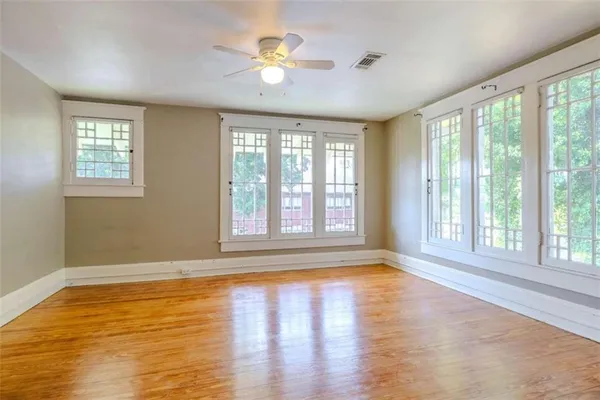 an empty room with wooden floor fan and windows