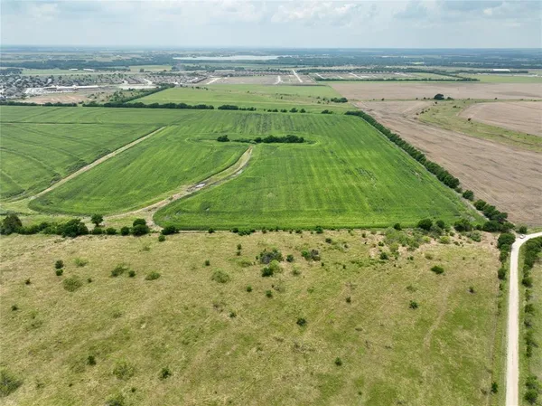a green field with lots of green space and trees in the background