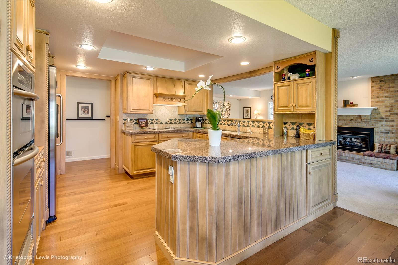 8247 Lodgepole Trail Lone Tree, CO 80124 - Photo 8 of 35 a kitchen with stainless steel appliances granite countertop a refrigerator a stove and a wooden cabinets
