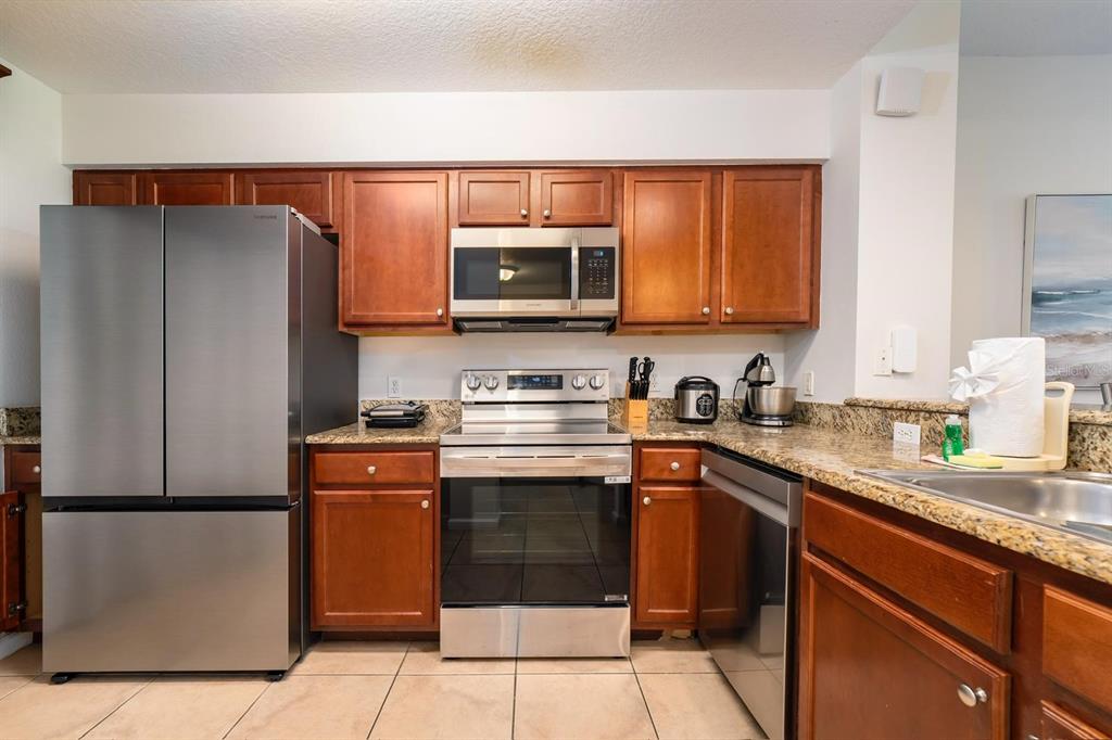 8763 Worldquest Boulevard, Unit 5406 Orlando, FL 32821 - Photo 14 of 25 a kitchen with stainless steel appliances granite countertop a refrigerator and a stove top oven