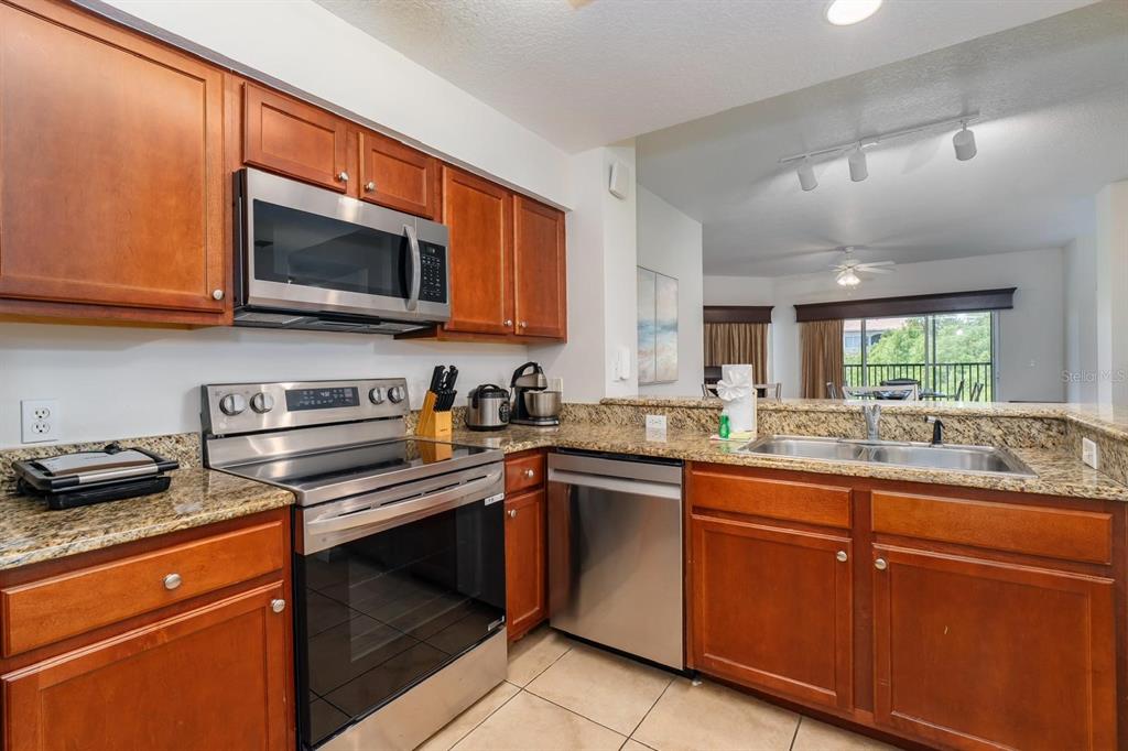 8763 Worldquest Boulevard, Unit 5406 Orlando, FL 32821 - Photo 16 of 25 a kitchen with stainless steel appliances granite countertop a stove microwave and sink