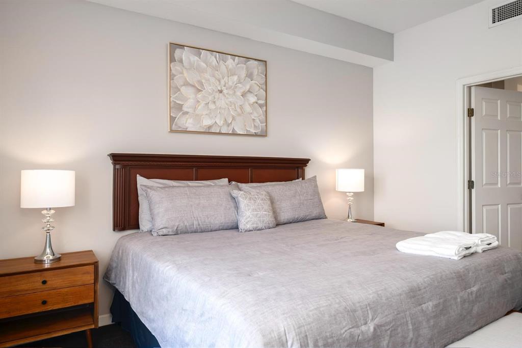 8763 Worldquest Boulevard, Unit 5406 Orlando, FL 32821 - Photo 18 of 25 a bedroom with a bed and a lamp on dresser