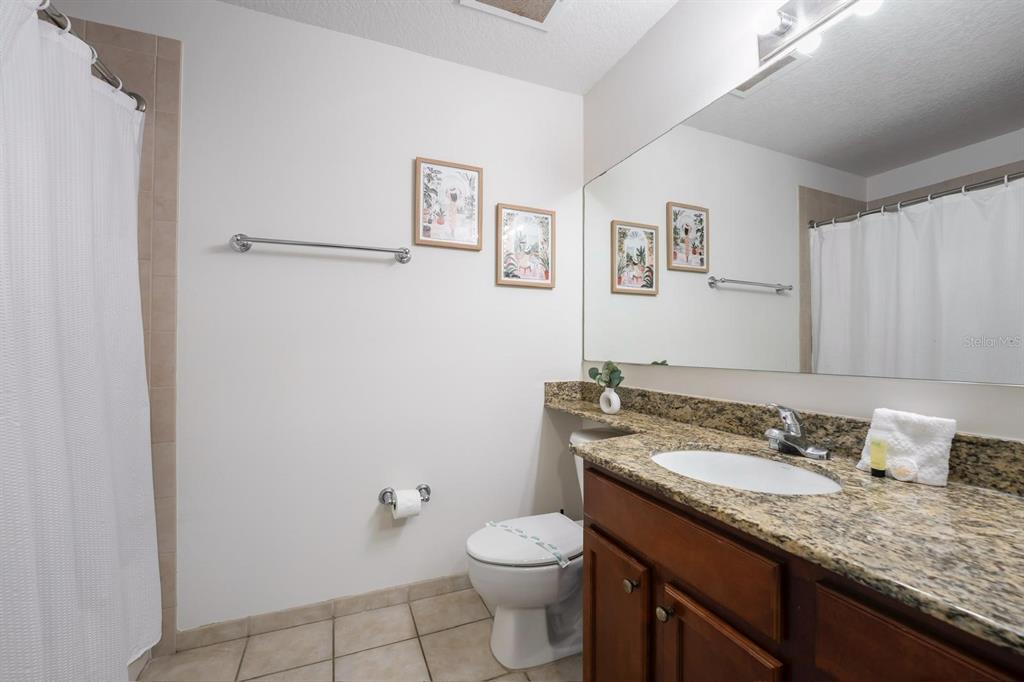 8763 Worldquest Boulevard, Unit 5406 Orlando, FL 32821 - Photo 24 of 25 a bathroom with a granite countertop sink a toilet and a mirror