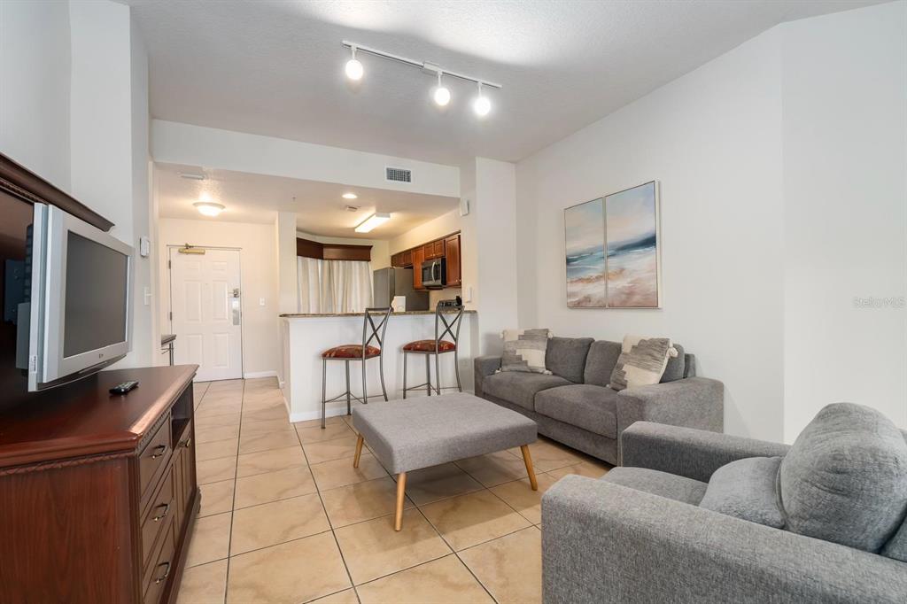 8763 Worldquest Boulevard, Unit 5406 Orlando, FL 32821 - Photo 8 of 25 a living room with furniture and a flat screen tv
