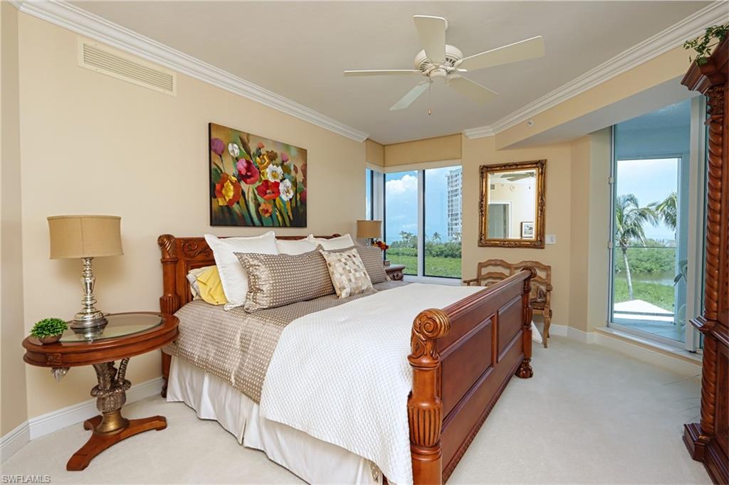 60 Seagate Drive, Unit 402 Naples, FL 34103 - Photo 11 of 26 a bed room with a bed and a chandelier