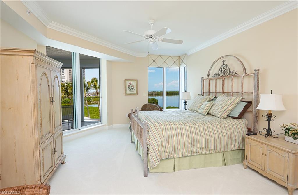 60 Seagate Drive, Unit 402 Naples, FL 34103 - Photo 17 of 26 a spacious bedroom with a bed and a chandelier