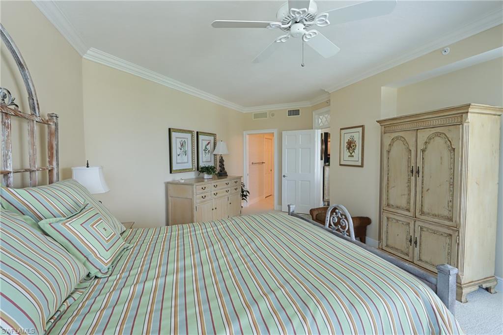 60 Seagate Drive, Unit 402 Naples, FL 34103 - Photo 18 of 26 a bedroom with a large bed and a chandelier