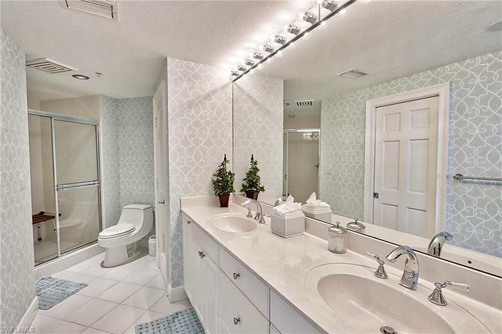 60 Seagate Drive, Unit 402 Naples, FL 34103 - Photo 19 of 26 a bathroom with a double vanity sink toilet and shower
