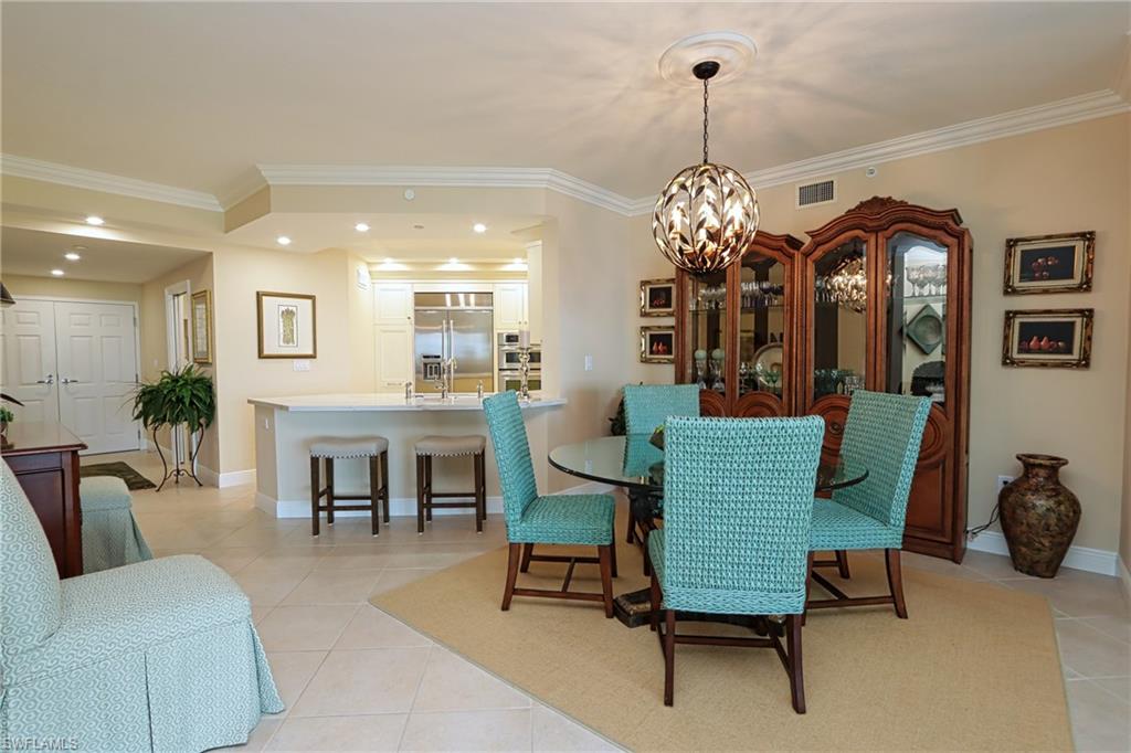 60 Seagate Drive, Unit 402 Naples, FL 34103 - Photo 7 of 26 a living room with furniture and a chandelier