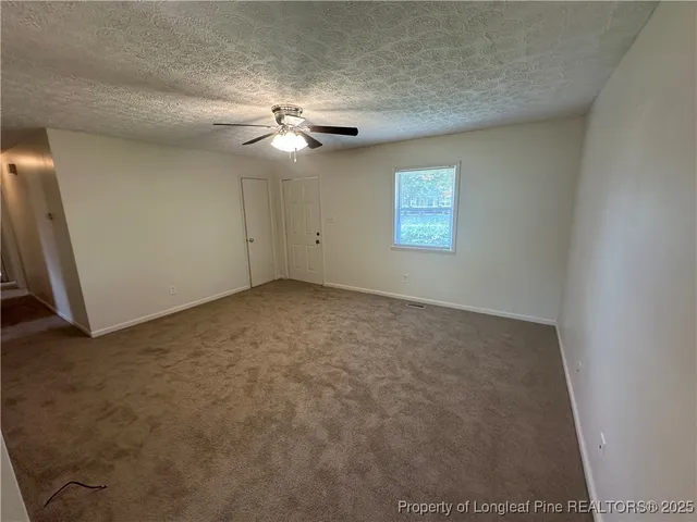 an empty room with windows and fan