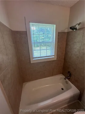 a bathroom with a tub a window and a shower