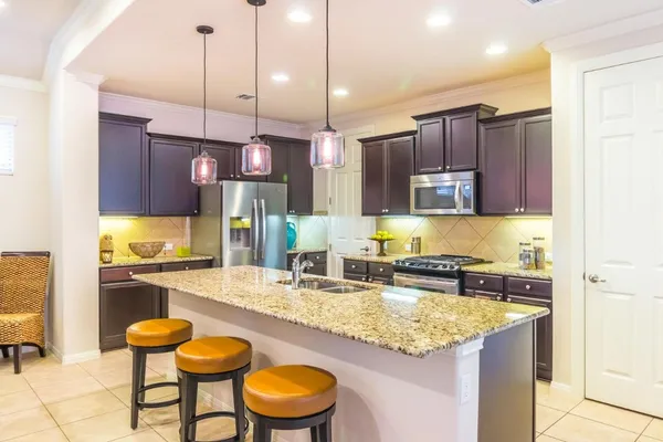 a kitchen with stainless steel appliances granite countertop a sink a stove and a wooden cabinets