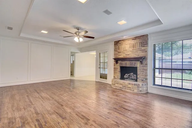 an empty room with windows fireplace and wooden floor