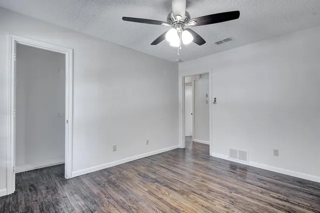 an empty room with wooden floor and ceiling fan