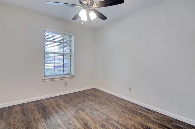 an empty room with a window and chandelier fan