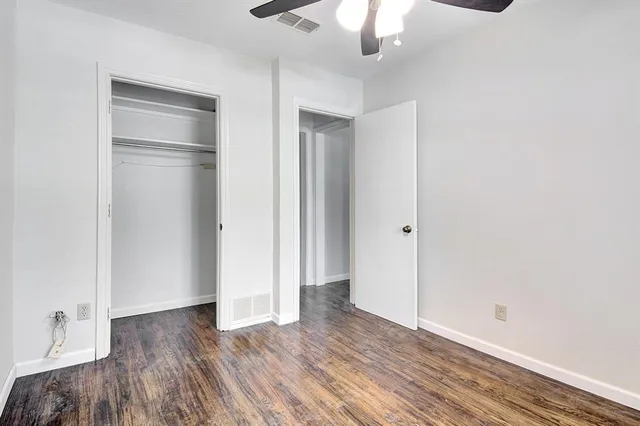 an empty room with wooden floor cabinet and windows