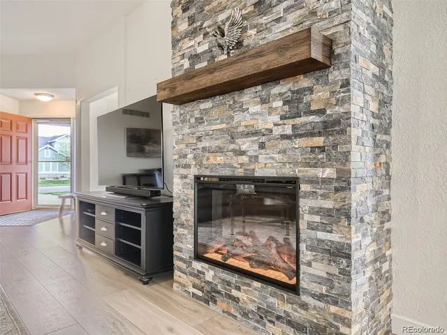 a living room with stainless steel appliances wooden floor and a fireplace