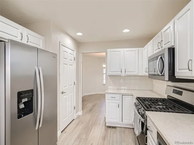 a kitchen with stainless steel appliances granite countertop a refrigerator and a stove top oven