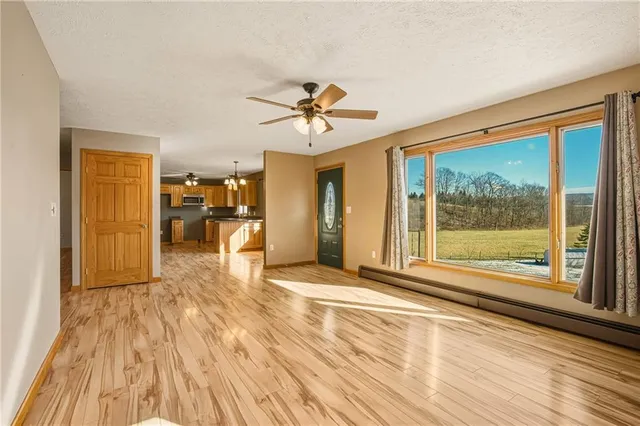 a view of empty room with wooden floor and fan