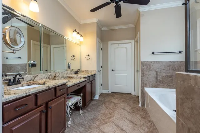 a spacious bathroom with a granite countertop sink a mirror and a bathtub
