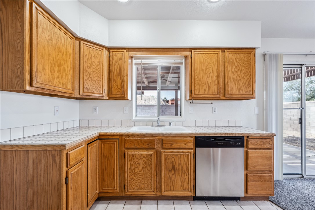 2524 South Ridge Avenue Bullhead City, AZ 86429 - Photo 22 of 64 Kitchen with dishwasher, a sink, tile countertops, and brown cabinets