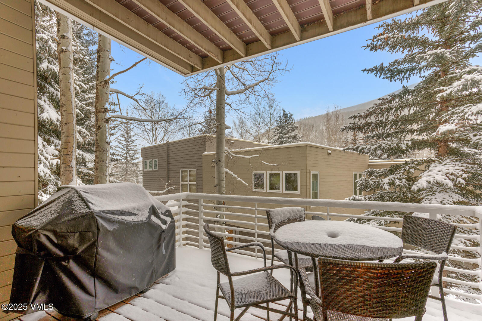 1230 Lions Ridge Loop, Unit 2D Vail, CO 81657 - Photo 12 of 42 a view of a patio with table and chairs and barbeque with wooden floor and fence