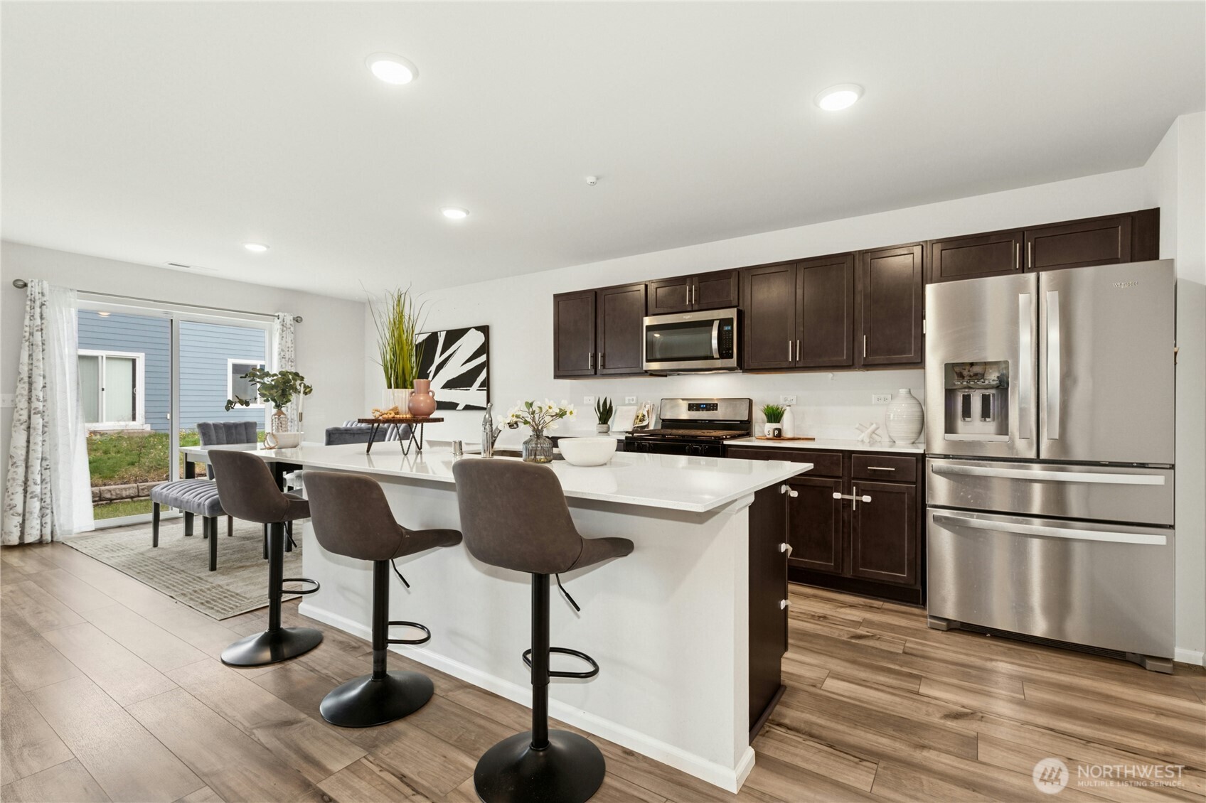 31233 122nd Street Southeast Sultan, WA 98294 - Photo 14 of 35 a kitchen with stainless steel appliances granite countertop a refrigerator a stove top oven a sink dishwasher a dining table and chairs with wooden floor