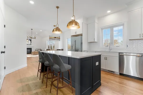 a kitchen with kitchen island granite countertop a sink a stove a dining table and chairs