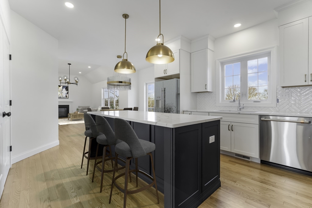 62 High Street, Unit LOT 7 Stoneham, MA 02180 - Photo 6 of 19 a kitchen with kitchen island granite countertop a sink a stove a dining table and chairs