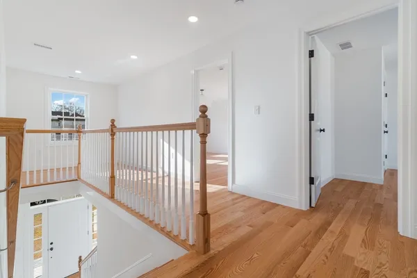 a view of a hallway with entryway and wooden floor