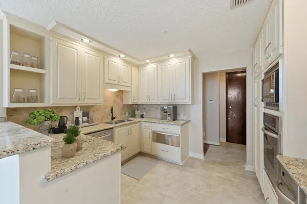 a kitchen with granite countertop a sink stove and refrigerator