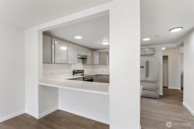 a view of a kitchen with a sink and dishwasher a refrigerator with wooden floor
