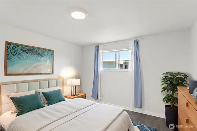 a bedroom with a bed lamp and potted plant on the dresser