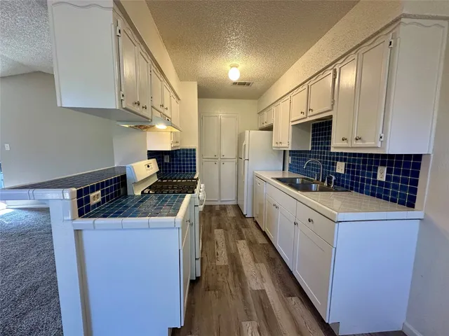 a kitchen with granite countertop a stove top oven and cabinets