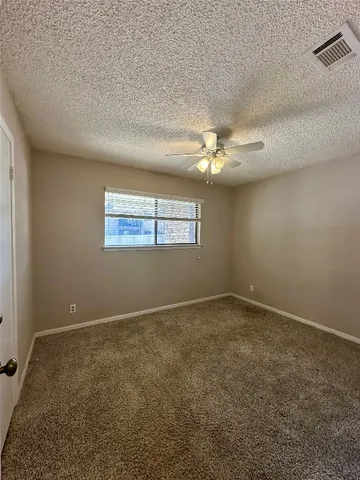 an empty room with a chandelier fan and windows