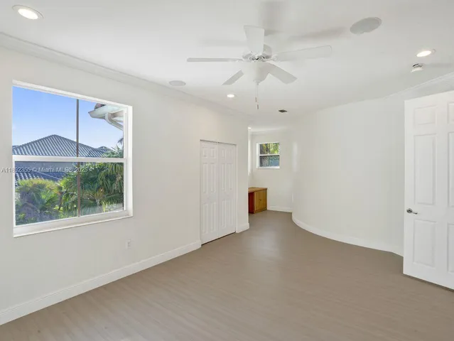 a view of empty room with wooden floor and fan