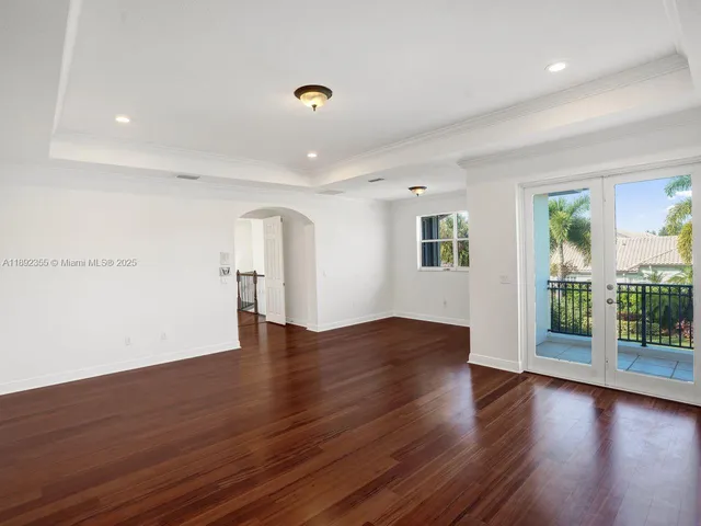 an empty room with wooden floor closet and windows