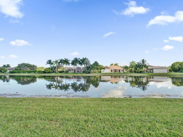a view of a house with a big yard and palm trees