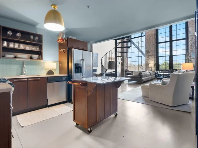 a large kitchen with kitchen island a large counter top space a large window and stainless steel appliances