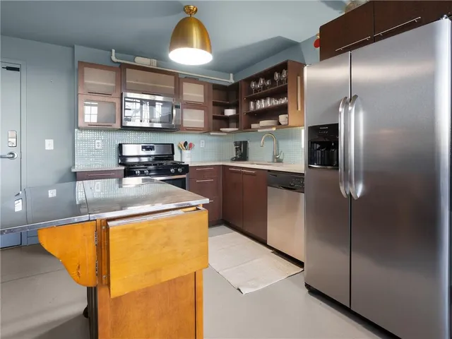 a kitchen with stainless steel appliances granite countertop a sink a stove and refrigerator