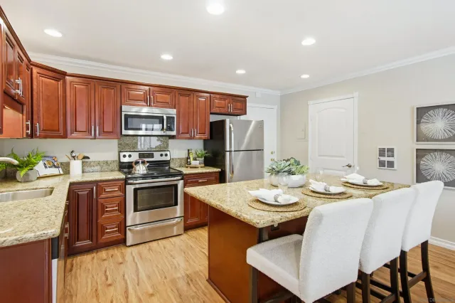 a large kitchen with stainless steel appliances granite countertop a stove a sink a dining table and chairs