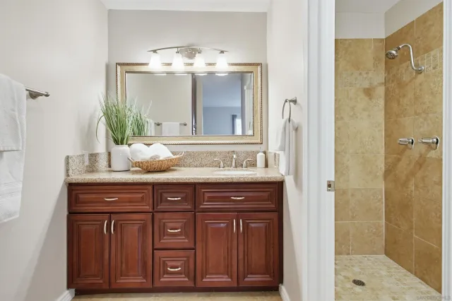 a bathroom with a granite countertop sink a mirror and a shower