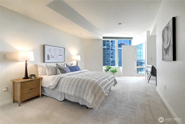 a spacious bedroom with a bed couch and a flat tv screen