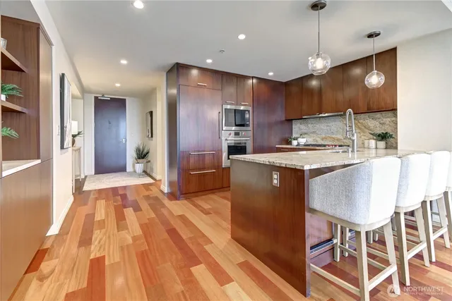 a large kitchen with stainless steel appliances kitchen island granite countertop a table chairs and a refrigerator
