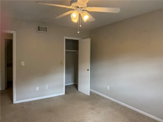 an empty room with a chandelier fan and closet area